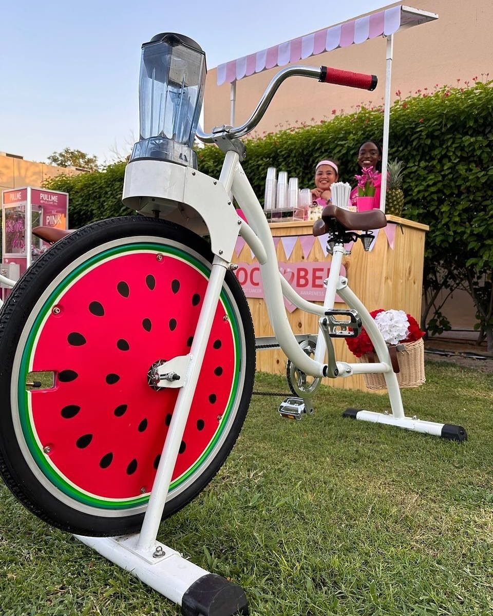 Sip & Cycle smoothie bike with a watermelon wheel serving guests at an outdoor event